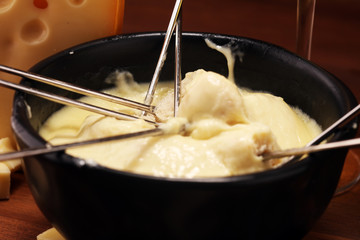Gourmet Swiss fondue dinner on a winter evening with assorted cheeses on a board alongside a heated pot of cheese fondue