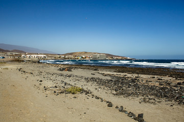 Beautiful coastal view of El Salado - Salted Beach. Shining clear blue sky over Horizon line, wave ripples on the turquoise water. El Medano, Tenerife