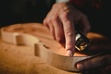 The hands of the luthier working on a violin © Riccardo Russo