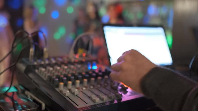 Close up of male hands turning knobs on professional DJ mixer console