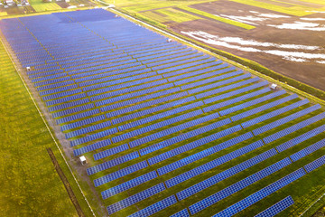 Large field of solar photo voltaic panels system producing renewable clean energy on green grass...