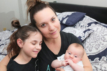Close up portrait of Young Beautiful Mother with two daughters, Cute 3 Month Old Baby Girl , 7 Years Old Girl, Happy Family, Happy Mother’s Day, Best Mother Concept, The Most Beautiful Girls in the wo
