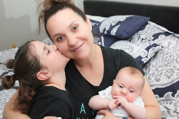 Close up portrait of Young Beautiful Mother with two daughters, Cute 3 Month Old Baby Girl , 7 Years Old Girl, Happy Family, Happy Mother’s Day, Best Mother Concept, The Most Beautiful Girls in the wo