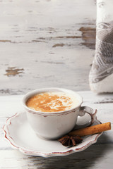 Beautiful cup of traditional indian masala chai tea on with star anise and cinnamon on a shabby wooden texture background