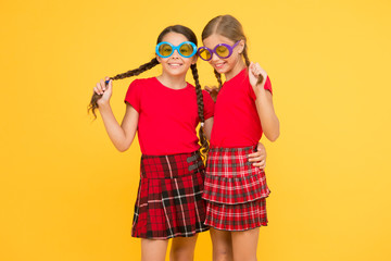 Summer fashion trend. Summer fun. Summer accessory. Girls cute sisters similar outfits wear colorful sunglasses for summer season. Kids fashionable friends posing in sunglasses on yellow background