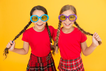 Summer accessory. Girls cute sisters similar outfits wear colorful sunglasses for summer season. Kids fashionable friends posing in sunglasses on yellow background. Summer fashion trend. Summer fun