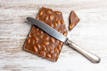 CHOCOLATE WITH ALMOND AND METAL KNIFE ON WOODEN BACKGROUND