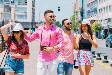 A couple of tourists is exploring a new city together. Smiling and making photos with a retro camera while walking at a city boardwalk.