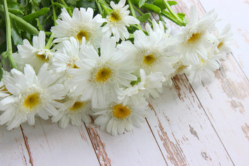 Obraz premium Bouquet of daisies on a white wooden background. Copy space.