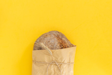 Fresh baked organic whole grain rye bread on bright yellow background