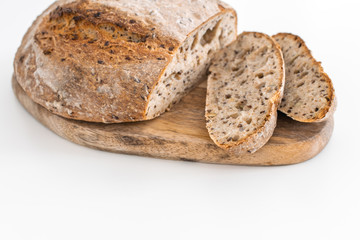 Fresh baked organic whole grain rye bread on wooden cutting board, white background