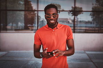 Portrait of happy smiling afro student in sunglasses over glass building.