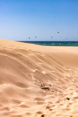 Fototapeta na wymiar SAND DUNES ON THE BEACH AND SAILS OF KITE SURF IN CADIZ, SPAIN