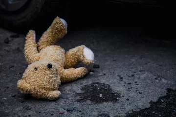 Fotobehang Concept: lost childhood, loneliness, pain and depression. Teddy bear lying down outdoors. © zwiebackesser