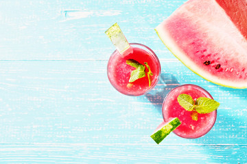 Watermelon summer cocktail with ice and mint leaves. Cold refreshment drink on blue wooden background with copy space.
