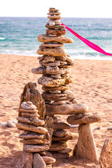 Fototapeta na wymiar STONE TOWER WITH PINK TIE AT THE TRAFALGAR BEACH IN CADIZ, SPAIN