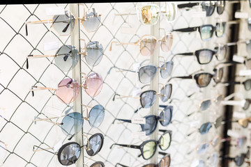 Many sunglasses rows at optical retail store. Rich assortment choice of different eyewear frames on eyeglasses shop display. UV protection for outdoor walking
