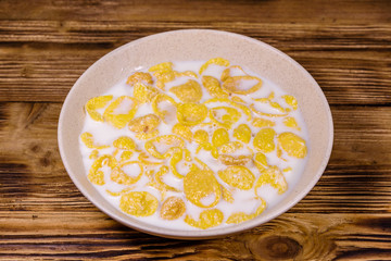 Ceramic plate with cornflakes and milk on a wooden table. Healthy eating