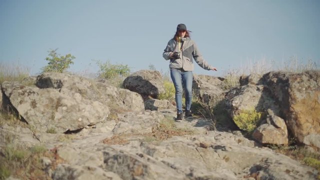 A young woman hiker walks in the mountains with photo camera