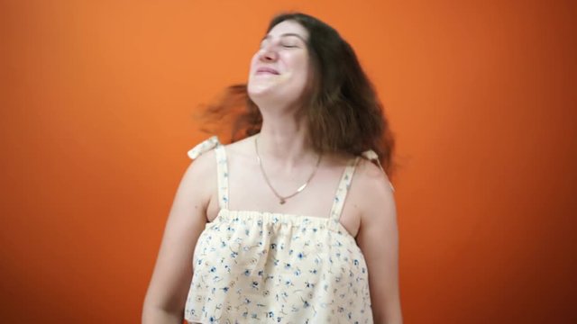 Woman laughing and smiling on orange background