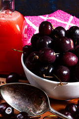CHERRIES IN BOWL WITH BOTTLE OF JUICE OF CHERRY AND METAL SPOON