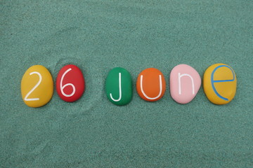 26 June, calendar date composed with multi colored stones over green sand