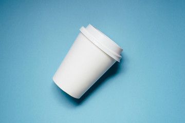 One paper cups for coffee or tea on blue background.