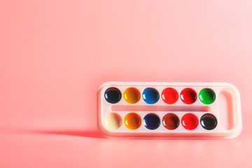 palette of acrylic paints on a pink background