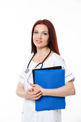 Happy young female family doctor holds blue folder with documents, has friendly expression, isolated white background. Medicine concept.