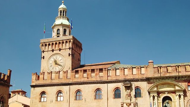 SLOW MOTION: clock tower of Palazzo d'Accursio or Comunale overlooking Piazza Maggiore, today the seat of the municipality of Bologna in Italy.