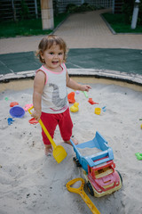 Fototapeta premium Baby girl in sandbox playing with toys