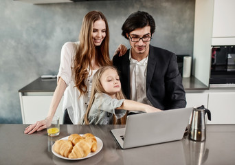 Happy little girl watching a movie on the computer with her father and mother