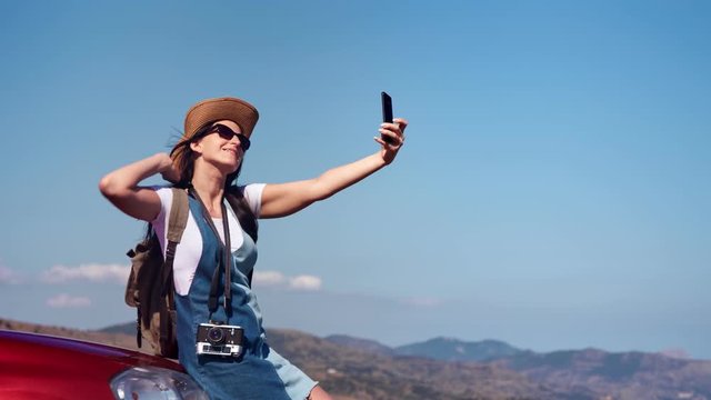Pleasant happy travel woman enjoying journey at mountain landscape taking selfie using smartphone