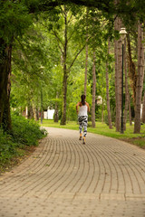 Fototapeta premium A beautiful fitness girl runs in the park. Nature and healthy life