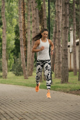  A beautiful fitness girl runs in the park. Nature and healthy life