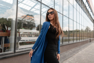 Beautiful hipster young woman in vintage sunglasses in a knitted long cape in a trendy T-shirt in...