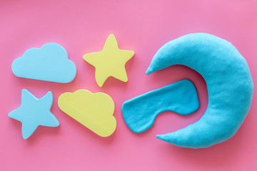 Sleep time concept with moon, stars, clouds, blindfolder on pink background top view