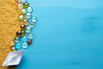 Small paper boat on the sandy shore. Creative minimal sea and beach concept. Rest on the sea. Copy space. Flat lay.