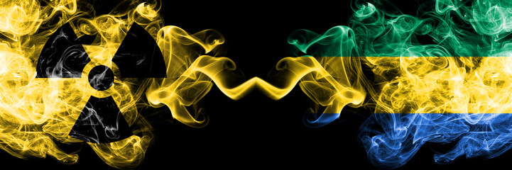 Gabon, Gabonese vs nuclear smoky mystic flags placed side by side. Thick colored silky smokes combination of Gabon, Gabonese flag and radioactive sign.