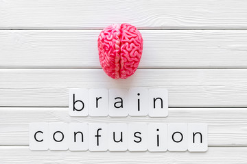 Brain functions and brain confusion concept with brain on white wooden background top view