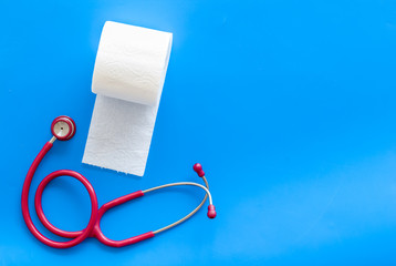 Toilet paper roll and stethoscope for proctology diseases concept on blue background top view mockup