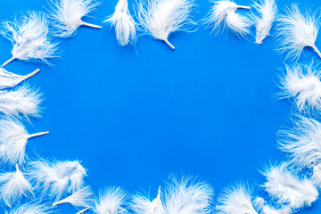 frame with feathers for modern design on blue background top view mock up