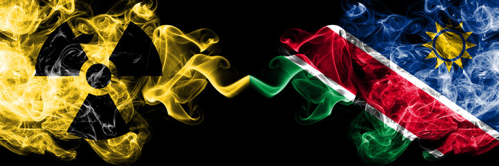Namibia, Namibian vs nuclear smoky mystic flags placed side by side. Thick colored silky smokes combination of Namibia, Namibian flag and radioactive sign.