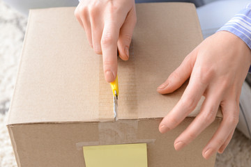 Young woman opening parcel at home, closeup