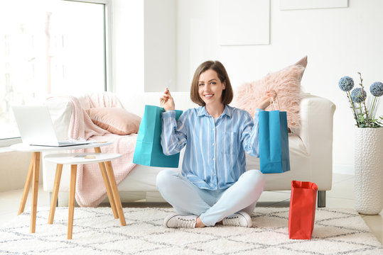 Young Woman With Shopping Bags Sitting At Home