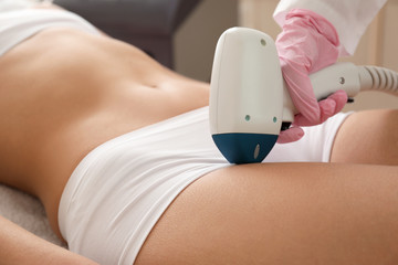 Beautiful woman undergoing procedure of laser hair removing in beauty salon