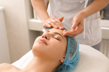 Beautiful woman undergoing facial treatment in beauty salon