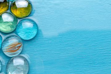 Glass round decorative stones on a blue background imitating large drops. Imitation of the sea. Vacation season.