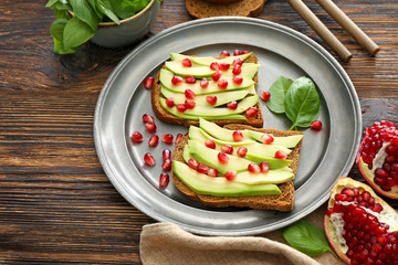 Plate with tasty avocado toasts on wooden table