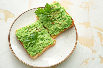 Plate with tasty avocado toasts on light background